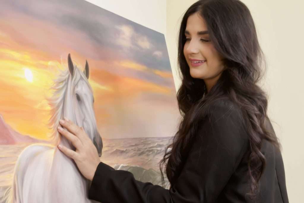 Sofia Brown artista colombiana tocando su obra de caballo pintada al oleo espatulado